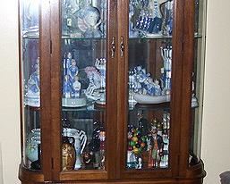 Tall display cabinet with Lladro and other porcelain figurines