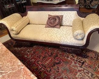 Empire Revival Mahogany Settee. Reeded rolled crest terminating in acorn finials above upholstered back, seat and rolled arms, the arms carved with rosettes and acanthus mounts, over cushion molded apron raised on lion paw feet with cornucopia and fruit brackets. American 77" length
