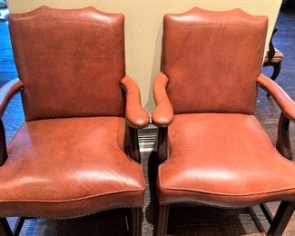 Two of four orange leather arm chairs