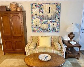 Beautiful living room with slipcovered loveseat, antique quarter sewn oak coffee table, antique cabinet and a Huge Andy Lakey original painting.