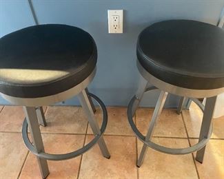Three brushed chrome and black barstools.