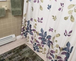 Bathroom set decor, shower curtain, flowers, picture, rug, towels.