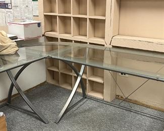 Glass corner L shaped desk. Metal legs and glass table top. 