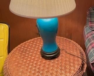 Round rattan end table and blue lamp.