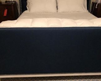 King-size bed in navy fabric with a tufted headboard and decorative nail tacks around the perimeter. Will be available from December 18th on. $1,200.