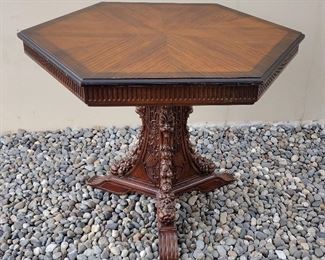  HEXAGONAL PEDESTAL SIDE TABLE: ORNATE BLACK FOREST TYPE BASE WITH NORTH WINDS FIGURES, FRUIT, AND SHIELDS/SPEARS