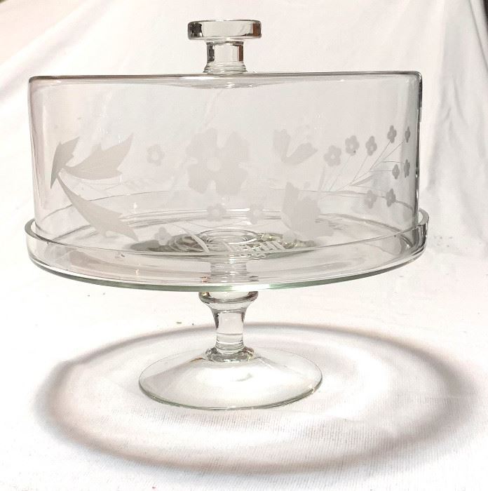 XL Glass Covered Cake Stand
($20 )
This is a large yet surprisingly delicate cake stand perfect for storing and displaying cakes, hors d’oeuvres, muffins and more. Stand features an elegant footed base and is topped by a glass dome. Skilled artisans hand etched a lovely floral design on the front of the cover. There are slight chips along the bottom edge where the cover meets the stand - the imperfections aren't visible due to the lip.