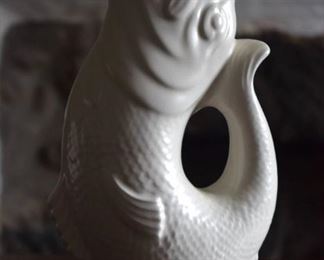 Vintage Fish Glug Jug
$40 

Variously called a glug jug or Dartmouth fish, the gurgling jug first appeared in 1800s and quickly became a best seller. This water jug takes the form of a fish with detailed scales with open mouth pointing straight up for pouring and with a curled up tail providing the handle. The jug is representative of various fish: perhaps a “little gurnard in the head, some bass for the body and a salmon-like tail.” The “gurgling” sound is produced when the jug is tipped up and it was designed in such a way that trapped air escapes from the tail as the liquid is poured. The jug, certainly a conversation piece to grace any table, was advertised as  “a novelty which always attracts attention” and certainly this is still true today.

Gluggle Jug/ Gurgle Jug/Gurggling Fish Jug/White Dartmouth England Gurgling Gluggle Koi Fish Vase Jug 

Marked Dartmouth Devon England on base