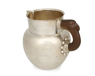 1027
A William Spratling "Eagle" Rosewood And Silver Pitcher
William Spratling (1900-1967)
Circa 1940-1944, First Design Period; Taxco, Mexico
Stamped for William Spratling; Further stamped: Spratling Silver / Made in Mexico
A pitcher with a smooth-finish body issuing to a carved rosewood handle in the form of an eagle head terminating in a hobnail handle junction

6 .25" H x 6.75" W x 4.75" D
16.545 gross oz. troy approximately
Estimate: $2,000 - $3,000