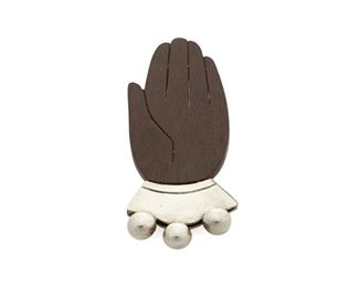 1065
A William Spratling Rosewood And Silver Brooch
William Spratling (1900-1967)
Circa 1940-1944, First Design Period; Taxco, Mexico
Stamped for William Spratling; Further stamped: Made in Mexico / Spratling Silver
Comprising a rosewood hand pin with silver cuff accented with three balls, with a double-pronged hinged clip fastener

1.375" H x 1.25" W
17.7 grams gross
Estimate: $500 - $700