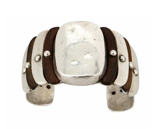 1096
A William Spratling Sterling Silver And Rosewood Cuff
William Spratling (1900-1967)
Circa 1940-1946, First Design Period; Taxco, Mexico
Stamped for William Spratling; Further stamped: Made in Mexico / Sterling / Spratling Silver
Comprising a cuff designed with alternating rosewood and silver crescent shapes

6.875" total inner C x 1.625" H, including a 1.375" gap
77.1 grams gross
Estimate: $1,000 - $1,500