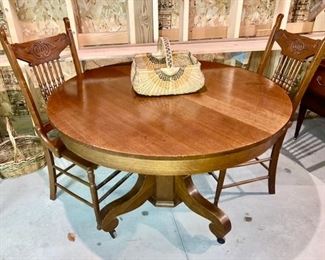 Antique round oak table with leaves, 2 pressed back chairs w/ leather seat insets