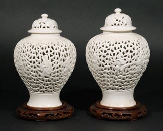Lot 81 |  PAIR CHINESE RETICULATED PORCELAIN VASES  |  Late Qing dynasty / early 20th century, blanc-de-chine lidded vases with figures among bamboo, with wood stands
h. 10-1/2 in.
overall: 11-1/2 in. (with stands)