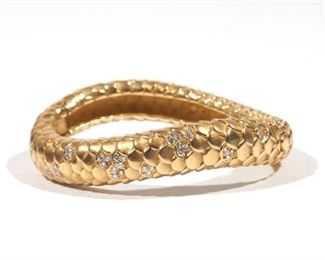 Lot 97  |  ANGELA CUMMINGS DIAMOND & 18K GOLD BRACELET  |  Of serpentine form with engraved scale pattern mounting clusters of round brilliant cut diamonds; interior 2-3/8 in., 95.1g, impressed "1986 / Cummings / 18K"