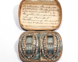 Lot 108  |  IMPORTANT AMERICAN PASTE SHOE BUCKLES  |  Each oval buckle mounting seventy-two intricately faceted cut glass "gemstones," the rectangular buckle opening decorated with engraved gold, finely crafted steel clips; in original box with hand-written family notes on provenance
h. 3 w. 2 in. (each buckle)
overall: h. 1-1/2 x 4-1/2 x 3-1/2 in. (box)