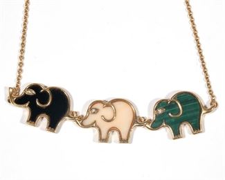Lot 109  |  VAN CLEEF & ARPELS ELEPHANT NECKLACE  |  Designed as three 18k yellow gold elephant links joined tail to tusk, one set with jet, one coral, and one malachite, each having a single diamond eye, signed, numbered, and with fineness mark on the feet, on a fine link gold chain; pendant l. 2-7/8 in.; 12.0g
overall: l. 14-3/4 in.

Accompanied by a Van Cleef & Arpels suede bag