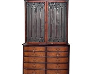 Lot 154  |  BESPOKE BEACON HILL GEORGIAN-STYLE BREAKFRONT  |  Two piece lockable stepback cabinet, the upper section with double glass doors, having individual panes of glass with the outer panes being slightly bent, opening to reveal three adjustable wooden shelves with plate grooves, with flared upper crest having carved decoration; the lower section with 10 half-length locking drawers and two serving slides, the top two drawers feature flatware inserts, with branded mark in second left drawer; upper section measures h. 50 x w. 49-3/4 x d. 17-3/4 in., bottom section measures h. 35-1/4 x w. 50-1/2 x d. 20 in.
h. 85-1/2 w. 53 d. 20 in.