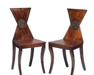 Lot 162  |  PAIR REGENCY HALL CHAIRS  |  With triangular hourglass backrests, each with a painted plaque, having splayed back legs and concave front legs
h. 35-1/2 w. 15-1/2 d. 18 in.
