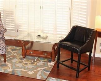 Wing back chair with ottoman, glass top coffee table, side table and lamp.