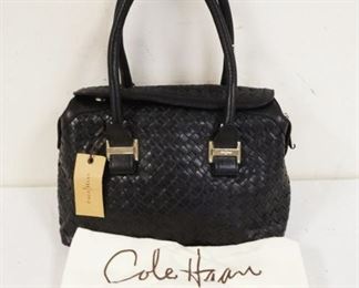 1034	COLE HANN BLACK LEATHER BASKET WEAVE BAG WITH DUST COVER, NEW WITH TAGS. APPROXIMATELY 12 IN L X 8 IN H X 5 IN
