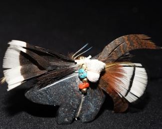 Slate bear fetish with turquoise, coral, and feathers.
