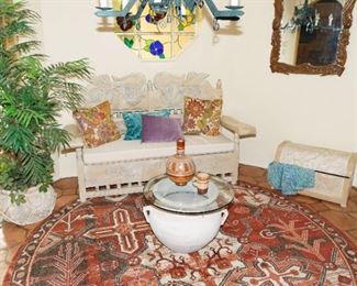 This vignette displays a handcarved wood bench, trunk, carved wood mirror and pottery