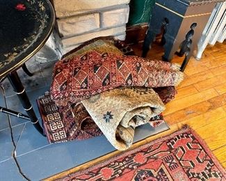 Stack of smaller antique area rugs.
