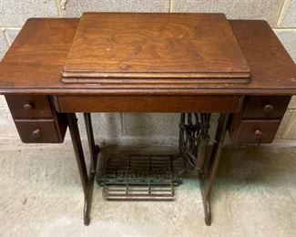 Vintage Singer sewing machine in cabinet with foot pedal