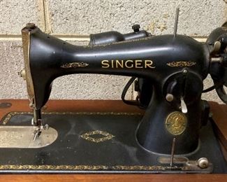 Vintage Singer sewing machine in cabinet with foot pedal