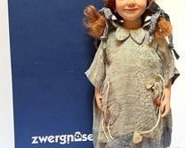 Zwergnase Celest Doll with box and certificate tag. (2000)
Number 76/250
She wears a grey and blue striped overdress with a mustard and light brown coloured underdress. On her feet, Celest wears real leather lace up boots and diamond patterned socks. She has a red human hair wig tied into two bunches.
Celest is 50cm tall and limited to 250 pieces