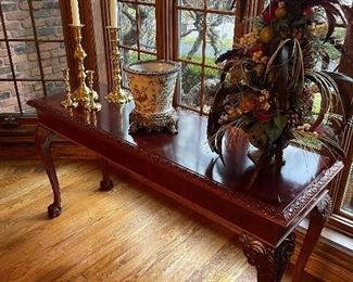 Console table with claw-ball feet, large brass taper candle holders, ceramic and brass planter, and holiday decor