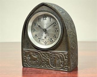 TIFFANY ZODIAC CLOCK  |  
Tiffany Studios New York desk clock with an arched bronze case, having zodiac designs replete with matching key in fitted holder on caseback door. - l. 4 1/4 x w. 2 x h. 5 1/4 in. (overall)