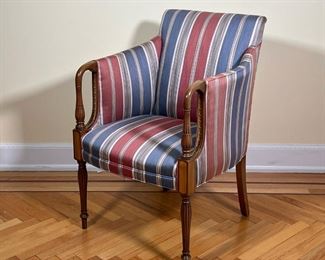 UPHOLSTERED ARMCHAIR  |  
With Hickory North Carolina label on the bottom, having striped upholstery on a bent and carved wood frame with intricate herringbone and lead decoration and contrasting words inside the arms and with contrasting wood at the knees over the fluted tapering legs - l. 24 x w. 24 x h. 36.5 in.