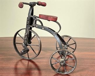 MINIATURE TRICYCLE  |
Small articulating metal tricycle having red wooden handle bars and a red wooden seat - h. 9 1/2 in.
