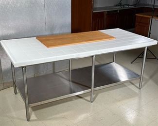 CHEF'S TABLE  |
White tile top with raised outer lip, permanently affixed wood cutting board surface, on an industrial 6 legged stainless steel frame - l. 88 x w. 40 x h. 36 in.