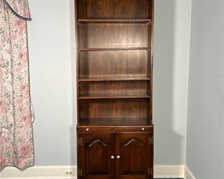 WOODEN BOOKCASE  |
Dark wood bookcase with four adjustable shelves over a pull out writing surface over double cabinet doors, having white porcelain poles and hammered metal hardware - l. 30 x w. 14.25 x h. 79.5 in.
