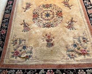 Living Room:  A carved Chinese rug with a black/floral  border and ivory color field with flowers measures 7' 9" x 10'  7," including the fringe.