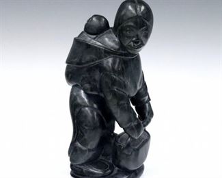 A contemporary Inuit stone carving.  Polished Black stone figure depicting a mother with gathering basket and child strapped to her back.  Signed "Eli" in syllabics, possibly Eli Elijassiapik (Canadian/Inuit (Inukjuak), 1936-2015) and dated "2006" with Canadian Igloo "Eskimo Art" certification tag at underside.  Minor surface wear.  9 1/2" high.  ESTIMATE $400-600
