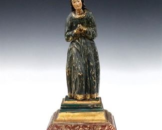 A 19th century Spanish Colonial carved wood Santos figure.  Depicts a female saint, possibly St. Anne, with polychrome decoration and Gilded detail.  Some wear, figure and top panel of stand detached.  15 3/4" high.  ESTIMATE $300-400
