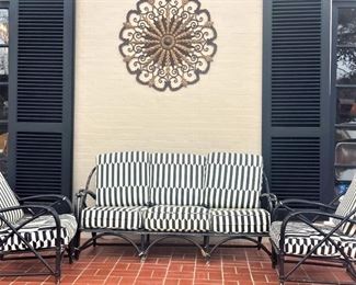 Black rattan patio furniture with black and white cushions; wall medallion