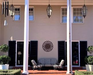 The east veranda offers black rattan patio furniture, wall medallion, and large wind chimes.