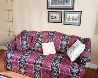 Red black and gold upholstered sofa. Several duck frame duck print