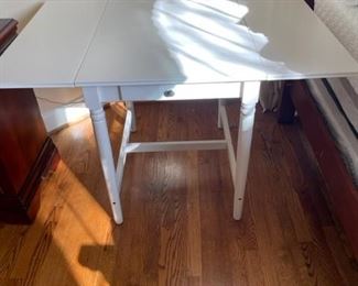 White drop-leaf table with drawer.
