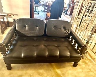 Black leather, mid century tufted love seat with solid wood spindals and rivits