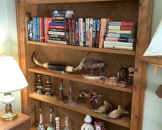 Books, many James Patterson, bull horns, wooden carved dog with duck in mouth, Indian heads, deer and ram head, alabaster lamps and candlesticks, dolls,