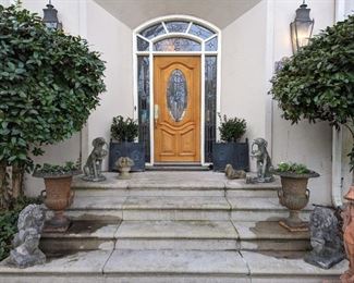 Inviting entrance, with metal French planters (wreath and finial detail) pair of vintage cast iron urn planters with handles, pair of vintage concrete lions, pair of concrete greyhounds carrying flower baskets, as they spontaneously tend to do, after chasing rabbits all day. There's also a concrete flower basket, dachshund and metal dachshund shoe scraper.