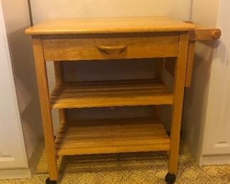 Rolling wood cart with cutting board top, knife block on right side, towel bar, single drawer and shelves. Measures 34.24inH x 35.25inW x 20.5inD