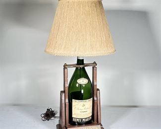 REMY MARTIN LAMP  |                                                        
Large E. Remy Martin Cognac bottle converted into a table lamp with a wooden stand / base, with a Remy Martin finial - l. 16 x w. 10 x h. 35 in. (overall)