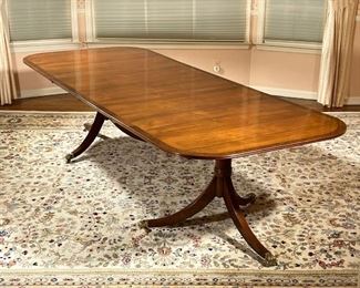 DOUBLE PEDESTAL DINING TABLE  |  Mahogany and burlwood veneer top, two pedestal sections raised on tripod bases with brass paw feet on casters; two leaves connected with brass clips; length without leaves 72 in. - l. 116 x w. 45 x h. 29 in. (with two leaves inserted)
