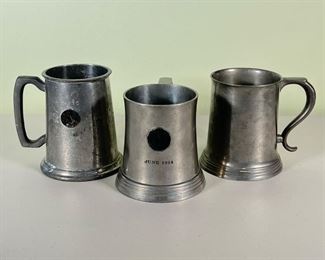 (3pc) VINTAGE PEWTER MUGS  |   Three pewter mugs with glass bottoms; one commemorating a 1975 2nd place sailboat race, one dated June 1914 from "The Jewellers 24 Karat Club of New York City" and one blank; makers marks on bottom, including one Reed & Barton and one Manning, Bowman & Co. - h. 5 x dia. 4 in. (largest)